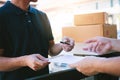 Young asian man smiling while delivering a cardboard box to the woman holding document to signing signature Royalty Free Stock Photo