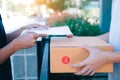 Young asian man smiling while delivering a cardboard box to the woman holding document to signing signature Royalty Free Stock Photo