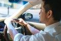 Young Asian man smiling and looking at the urban road while driving a car in city Royalty Free Stock Photo