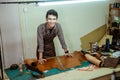 Young asian man smiling at work making patterns from leather