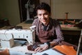 Young asian man smiling while working sewing leather material