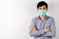 Young Asian man standing arms crossed wearing sanitation mask on face on white background in studio and looking at the camer Royalty Free Stock Photo