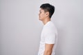 Young asian man standing over white background looking to side, relax profile pose with natural face and confident smile Royalty Free Stock Photo