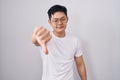 Young asian man standing over white background looking unhappy and angry showing rejection and negative with thumbs down gesture Royalty Free Stock Photo