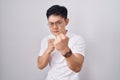 Young asian man standing over white background ready to fight with fist defense gesture, angry and upset face, afraid of problem Royalty Free Stock Photo