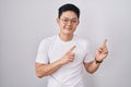 Young asian man standing over white background smiling and looking at the camera pointing with two hands and fingers to the side Royalty Free Stock Photo