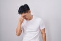 Young asian man standing over white background tired rubbing nose and eyes feeling fatigue and headache Royalty Free Stock Photo