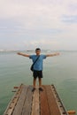 An Asian man standing with spreaded arms at the edge of a wooden pier Royalty Free Stock Photo