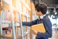 Young Asian man student choosing book in library Royalty Free Stock Photo