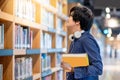 Young Asian man student choosing book in library Royalty Free Stock Photo