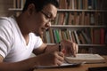 Young Asian man studying in library, exam preparation concept. Male college student doing research and making notes in his book Royalty Free Stock Photo
