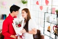 A young Asian man surprised his girlfriend by giving her a rose and flower bouquet for her anniversary date at home. Asian woman Royalty Free Stock Photo