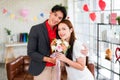 A young Asian man surprised his girlfriend by giving her a rose and flower bouquet for her anniversary date at home. Royalty Free Stock Photo