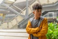 Young Asian man thinking with arms crossed in the city outdoors with rain Royalty Free Stock Photo