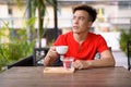Young Asian man thinking at the coffee shop outdoors Royalty Free Stock Photo