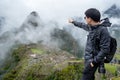 Young Asian man traveler pointing at Machu Picchu