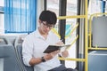 Young Asian man traveler sitting on a bus and reading book or practice homework exam while smile of happy day, transport, tourism Royalty Free Stock Photo