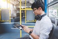 Young Asian man traveler sitting on a bus using tablet watch video or playing game while smile of happy, transport, tourism and r Royalty Free Stock Photo