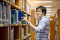 Young Asian man university student choosing book in library Royalty Free Stock Photo