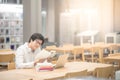 Young Asian man university student reading book in library Royalty Free Stock Photo
