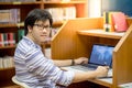 Young Asian man university student using laptop in library Royalty Free Stock Photo