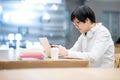 Young Asian man university student using smartphone in library Royalty Free Stock Photo