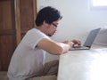 Young Asian man using computer laptop in living room. Internet of things Royalty Free Stock Photo