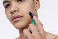 A young asian man using a disposable razor to cleanly shave the sideburns. Closeup tight shot isolated on a white backdrop