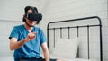 Young Asian man using glasses virtual reality simulator playing video game in bedroom, Japanese male feeling happy using relax Royalty Free Stock Photo