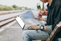 Young asian man using laptop and check map for working and search location for travel at train station. Freelance work and travel Royalty Free Stock Photo