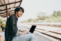 Young asian man using laptop for working and search location for travel at train station. Freelance work and travel concept Royalty Free Stock Photo