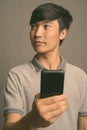 Young Asian man using mobile phone against gray background Royalty Free Stock Photo