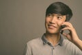 Young Asian man using mobile phone against gray background Royalty Free Stock Photo