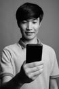 Young Asian man using mobile phone against gray background Royalty Free Stock Photo