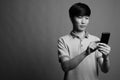 Young Asian man using mobile phone against gray background Royalty Free Stock Photo