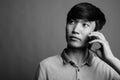 Young Asian man using mobile phone against gray background Royalty Free Stock Photo