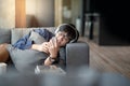 Young Asian man using smartphone relaxing on sofa Royalty Free Stock Photo