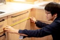 Young Asian man using tape measure for measuring furniture Royalty Free Stock Photo