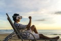 Young Asian man using virtual reality glasses for business meeting on the tropical beach over beautiful sea and sky background Royalty Free Stock Photo