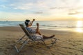 Young Asian man using virtual reality glasses for business meeting on the tropical beach over beautiful sea and sky background Royalty Free Stock Photo