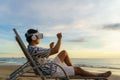 Young Asian man using virtual reality glasses for business meeting on the tropical beach over beautiful sea and sky background Royalty Free Stock Photo