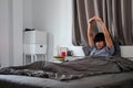 Young asian man waking up in bed and stretching his arms Royalty Free Stock Photo