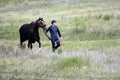 Young Asian man is walking with his pure breed Kazakh horse in Kazakhstan steppe