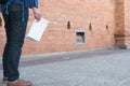 young asian man wearing blue shirt and jeans with map and backpack standing near old brick wall Royalty Free Stock Photo