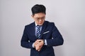 Young asian man wearing business suit and tie checking the time on wrist watch, relaxed and confident Royalty Free Stock Photo