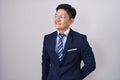 Young asian man wearing business suit and tie looking away to side with smile on face, natural expression Royalty Free Stock Photo