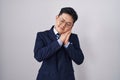 Young asian man wearing business suit and tie sleeping tired dreaming and posing with hands together while smiling with closed Royalty Free Stock Photo