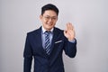 Young asian man wearing business suit and tie waiving saying hello happy and smiling, friendly welcome gesture Royalty Free Stock Photo