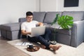 Young Asian man wearing eyes glasses sitting on floor working from home using laptop computer for working. Work from home concept Royalty Free Stock Photo