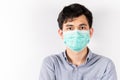 Young Asian man wearing green sanitation mask on face on white background in studio and looking at the camera. COVID-19 concept. Royalty Free Stock Photo